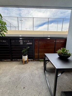 Eine Terrasse mit Tisch, Stühlen, einem Blumentopf und einem Zaun.