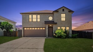 A two-story house with a garage, a front porch, and a well-maintained lawn. - Spacious 4BR San Antonio Home w/ Private Pool, Game Rooms & Gym (San Antonio)