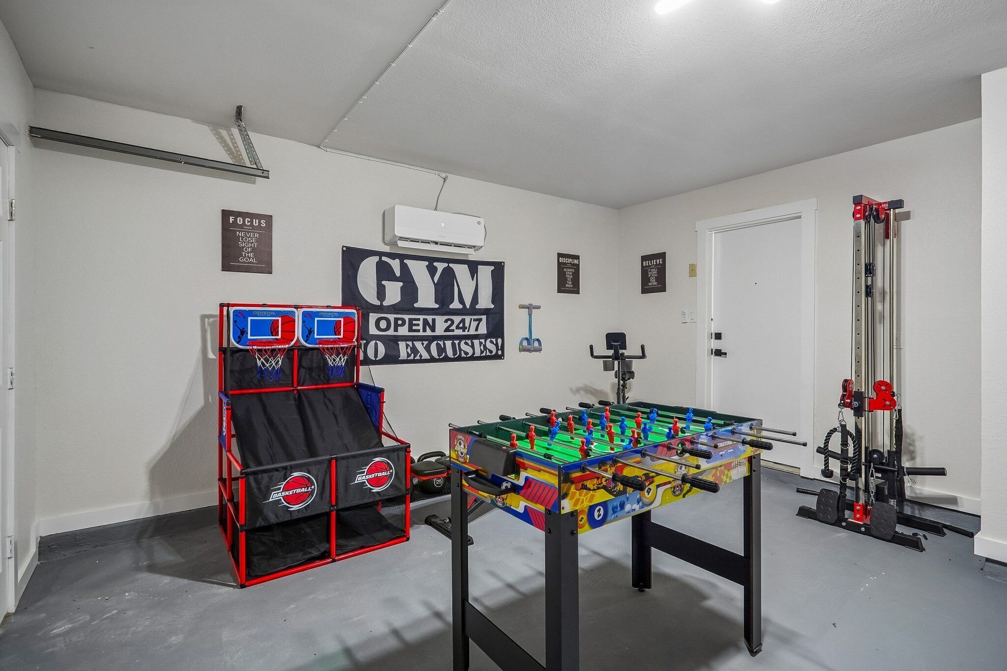 A gym with a foosball table, a basketball hoop, and a weightlifting area.