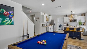 A modern living space with a pool table, kitchen, and dining area. - Spacious 4BR San Antonio Home w/ Private Pool, Game Rooms & Gym (San Antonio)