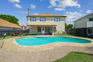 Ein Wohnhaus mit Swimmingpool, überdachter Terrasse und umzäunter Garten.