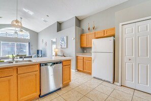 A kitchen with wooden cabinets, a dishwasher, a refrigerator, and a window providing natural light. - Spacious 4-bedroom house with AC in charming Davenport (Davenport)