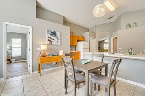 Een moderne keuken met houten kastjes, een eettafel met stoelen en een hanglamp.