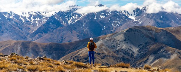 A person standing on a rocky outcrop with a mountainous landscape in the background.