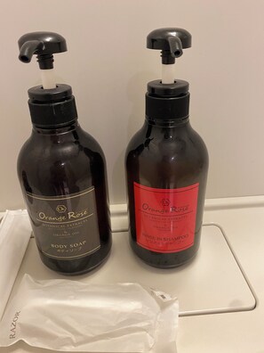 Dois frascos de sabonete líquido e shampoo Orange Rose sobre uma superfície branca.