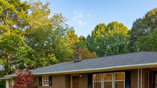 Een gelijkvloers bakstenen huis met een veranda, gazon en oprit.