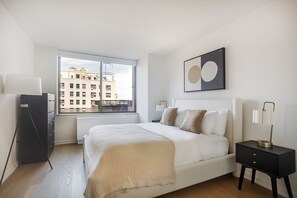 A modern bedroom with a large window, a bed, bedside tables, and a floor lamp. - Blueground | Upper West Side, rooftop, nr Central Park (New York)