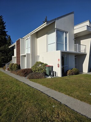 A modern two-story building with a flat roof, large windows, and a small balcony.
