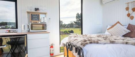 Een slaapkamer met een bed, een bureau, een magnetron en uitzicht op de omgeving.