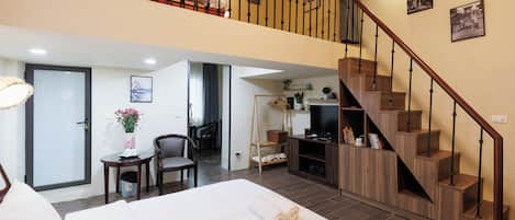 Habitación de hotel con cama, escritorio, silla, televisor y escalera.
