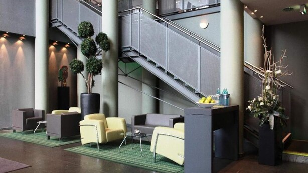 Een hal met een trap, zithoek en decoratieve planten.