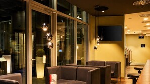 Een moderne zithoek met lederen banken, kleine ronde tafels en hanglampen.