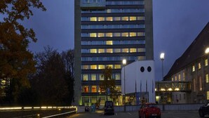 Een meerlaags gebouw met een modern architectonisch ontwerp, met een reeks ramen en een plat dak.