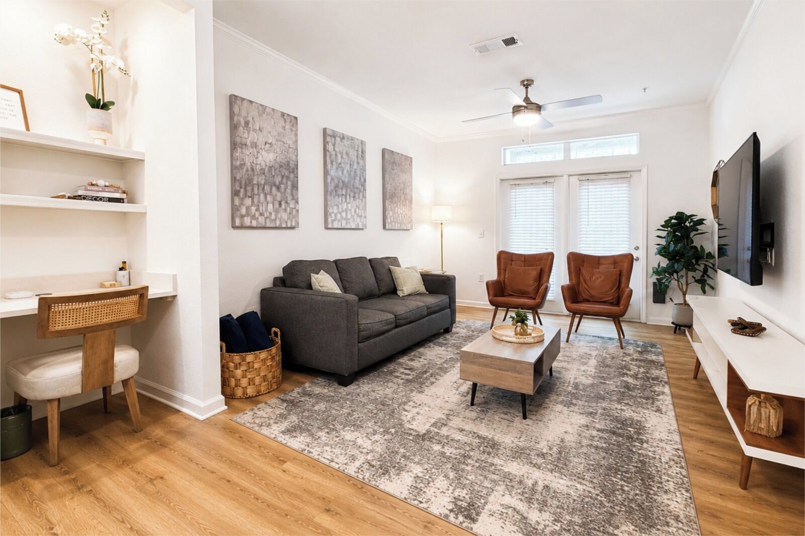 A living room with a sofa, two armchairs, a coffee table, a TV, and artwork on the walls.