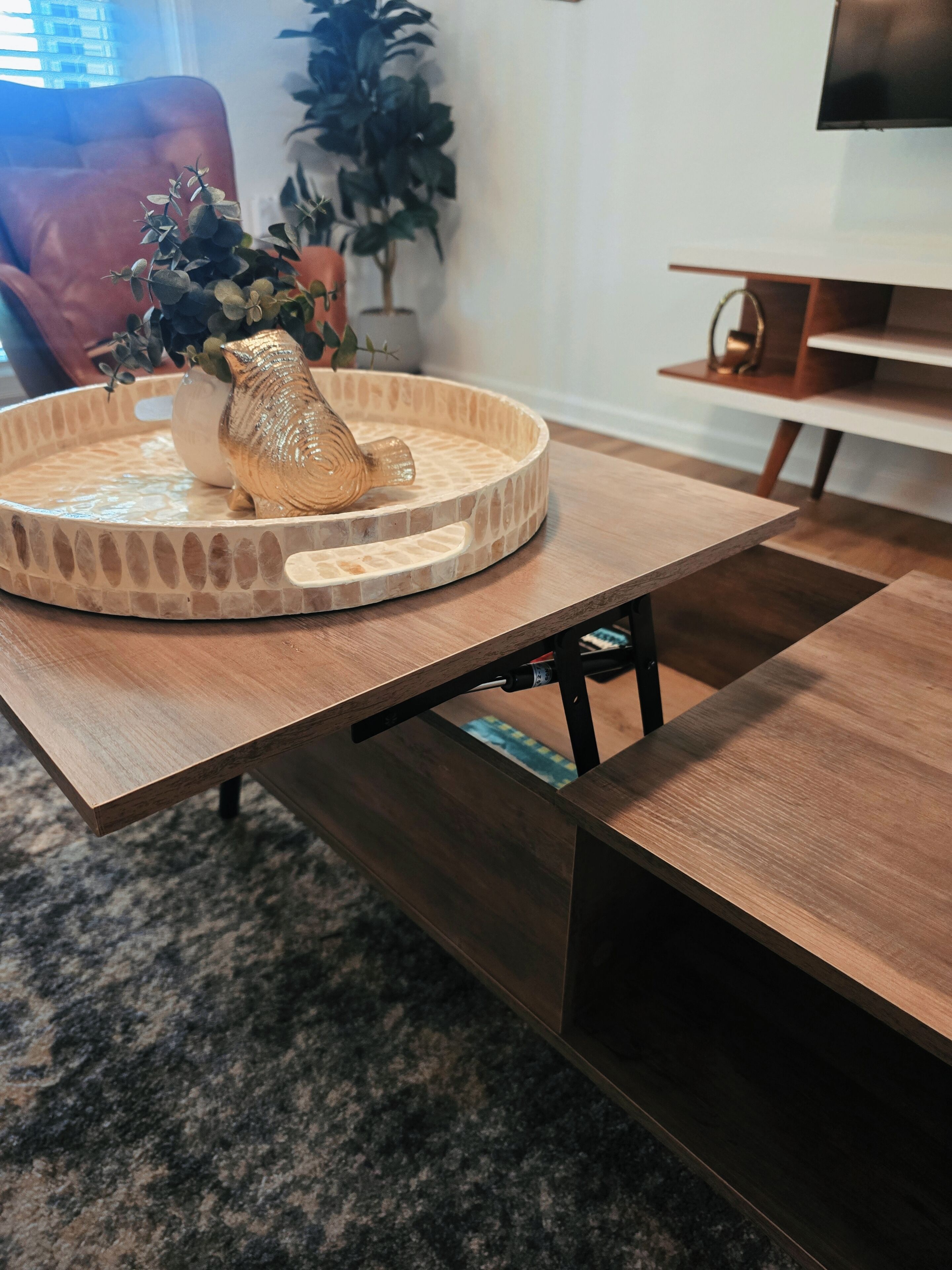 A wooden table with a decorative bowl and a plant on it.