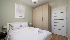 A bedroom with a bed, a map of Warsaw, a wardrobe, and a door. - Aleja Krakowska Lavish Apartment (Warszawa)
