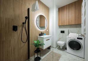 Ein modernes Badezimmer mit einem hölzernen Waschtisch, einem runden Spiegel, einer Toilette und einer Waschmaschine.