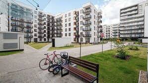 A modern apartment complex with multiple balconies, a paved walkway, and a bench. - Aleja Krakowska Lavish Apartment (Warszawa)