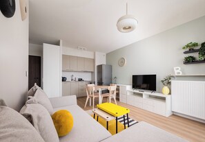 Ein modernes Wohnzimmer mit einer Couch, einem gelben Hocker und einem Fernseher.