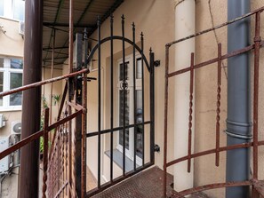 Una verja de metal con un ojo de cerradura, una escalera y una pared color beige.