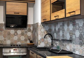 A kitchen with wooden cabinets, a stainless steel oven, and a patterned backsplash. - Heart of Cracow Cosy Apartment (Kraków)