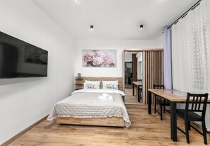 A modern bedroom with a bed, a TV, a painting, and a dining area. - Heart of Cracow Cosy Apartment (Kraków)