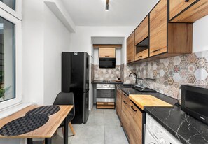 Una cocina compacta con refrigerador, horno, lavaplatos y armarios de madera.
