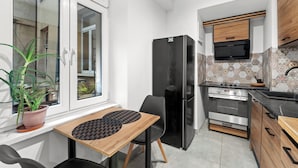 Eine kleine Küche mit Kühlschrank, Herd und einem Essbereich mit Tisch und Stühlen.