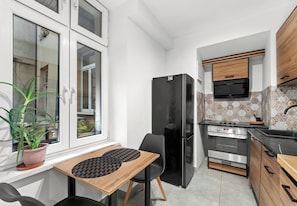 Eine kleine Küche mit Kühlschrank, Herd und einem Essbereich mit Tisch und Stühlen.