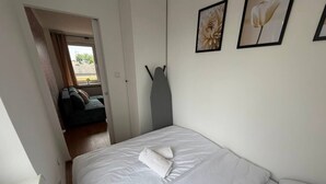 Ein Schlafzimmer mit einem Bett, einer Tür zu einem anderen Raum und zwei gerahmten Bildern an der Wand.