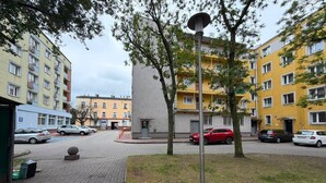 Ein Wohngebiet mit mehrstöckigen Gebäuden, einem gepflasterten Gehweg und parkenden Autos.