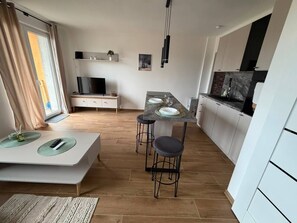 Une cuisine moderne avec un coin repas, un plancher en bois et des meubles de rangement blancs.
