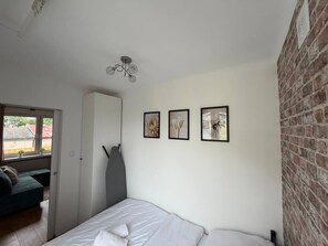 Un dormitorio con cama, armario, puerta y pared de ladrillo.