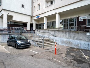 A building with a staircase leading to an entrance, a parked car, and a wheelchair accessibility sign. - Piotrkowska Spacious Apartment (Łódź)