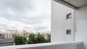 Uma varanda com vista para a paisagem urbana, incluindo edifícios e uma estrada.