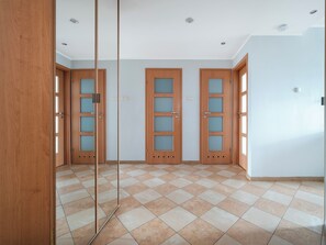 A room with three wooden doors, a tiled floor, and recessed ceiling lights. - Piotrkowska Spacious Apartment (Łódź)