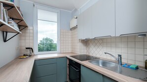 Cozinha moderna com janela, estantes embutidas, pia e máquina de lavar loiça.