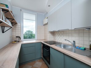A modern kitchen with a window, built-in shelves, a sink, and a dishwasher. - Piotrkowska Spacious Apartment (Łódź)