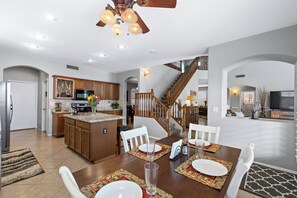 A spacious kitchen with wooden cabinets, a central island, and a dining area with a table set for four.