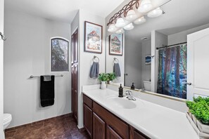 A bathroom with a white sink, a mirror, a towel rack, and a shower curtain.