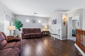 A living room with a brown sofa, a lamp, a plant, and a wall clock. - 🏜 CANDLEWOOD DESERT OASIS IN JOHNSON RANCH: PRIVATE POOL, RELAX AND ENJOY! 🏝 (San Tan Valley)
