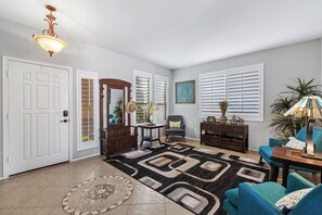 A spacious living room with a large window, a fireplace, a coffee table, and a blue sofa.