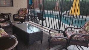 Eine Terrasse mit Korbmöbeln, einem Pool und einem Neonzeichen.