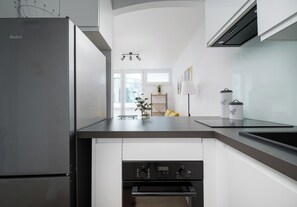Une cuisine moderne dotée d’un réfrigérateur en acier inoxydable, d’un four encastré et d’un plan de travail noir.