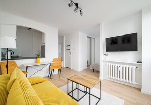 Un salon moderne avec un canapé, une table basse et un téléviseur fixé au mur.