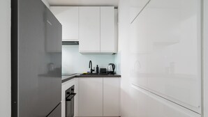 A compact kitchen with white cabinets, a stainless steel refrigerator, and a built-in oven. - Park Mirowski Central Apartment (Warszawa)
