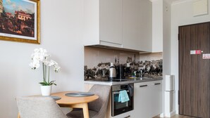 Uma cozinha moderna com área de refeições, exibindo uma pintura, orquídeas e vista para a cidade.