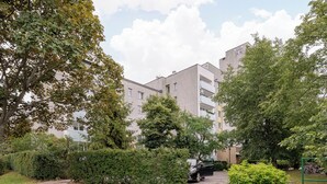 A residential building with multiple balconies, surrounded by mature trees and a well-maintained lawn. - Wilanów Comfort Stay Apartment (Warszawa)