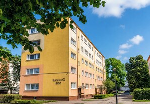 Ein mehrstöckiges Gebäude mit einer gelben Fassade, mit der Aufschrift 'Bukowska 120 abc'.