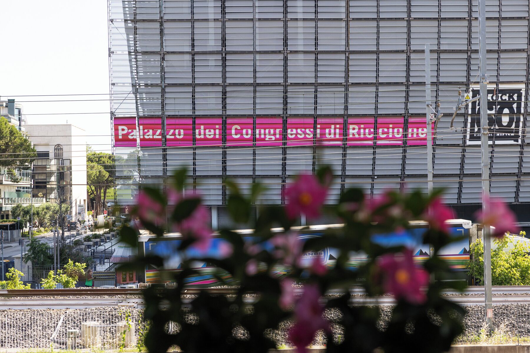 Suuri, vaaleanpunainen kyltti, jossa lukee »Palazzo dei Congressi di Riccione», koristelee rakennuksen julkisivua.